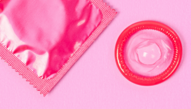 Pink condom with pink wrapper on pink background