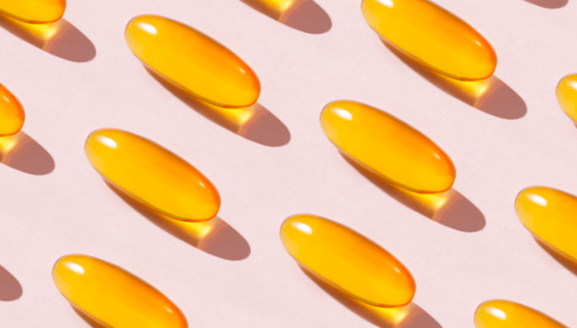 Pink background with yellow liquid supplement capsules